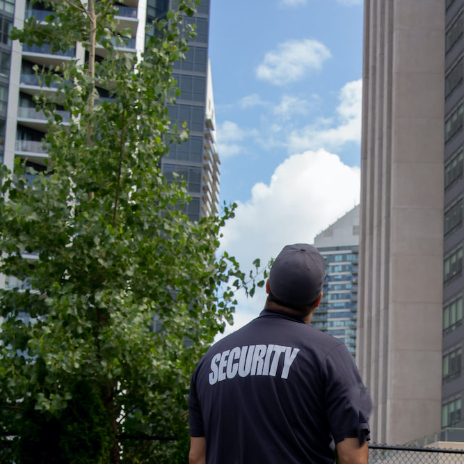 Security guard looking at tall buildings